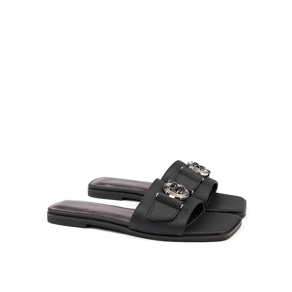 Pebbled black leather flat mule with silver circular logo and dark rubber sole