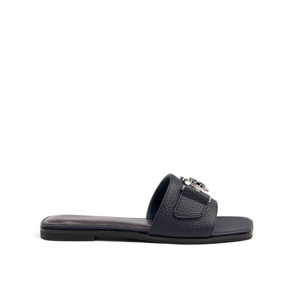 Navy pebbled leather flat slide sandal with silver logo medallion side view